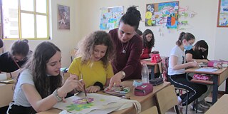 Schüler und Schülerinnen lernen mit Lehrkraft im Klassenzimmer