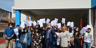 Gruppenfoto vor dem Schuleingang von Schülern und Lehrkräften mit medizinischen Mund-Nase-Masken