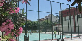 Blick auf den Sportplatz, auf dem zwei Personen Tennis spielen