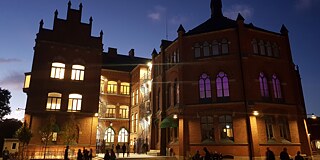 Beleuchtetes Gebäude am Abend mit Menschen vor dem Gebäude