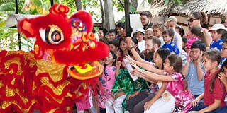 Ein rot verkleideter Drachen besucht Schulkinder