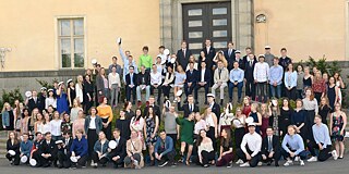 Gruppenfoto von Schülerinnen und Schülern vor dem gelben Schulgebäude