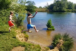 Zwei Jungs springen in einen Weiher.