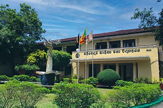 Gebäude der Maliyadeva Baika Vidyalaya mit Flaggen und Statue