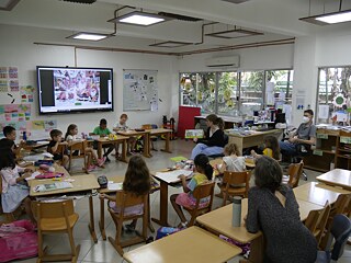 Lehrerin sitzt inmitten einer Schulklasse im Klassenzimmer