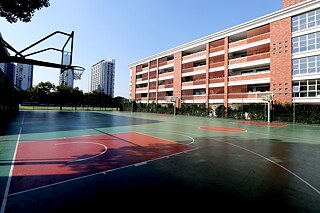 Basketballplatz, im Hintergrund längliches Gebäude und Hochhaus