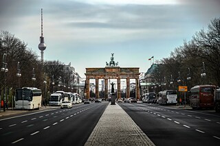 Blick aufs Brandenburger Tor, von der Mitte der Straße aus aufgenommen. Links im Hintergrund sieht man den Fernsehturm, rechts das Hotel Adlon.