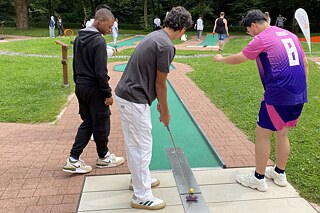 Die Jugendlichen spielen Minigolf.