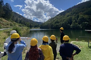 Jugendliche mit Sicherheitshelmen blicken auf einen See.