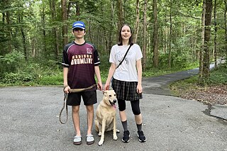 Jugendliche mit einem Hund auf einem gefestigten Waldweg