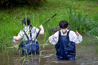 Ein Schüler und eine Schülerin säubern einen Teich